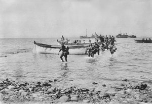 Ausztrál katonák gázolnak át a vízen, amint partra szállnak a gallipoli Anzac Cove-nál 1915. április 25-én, miután a háttérben lévő nagyobb hajókról partraszálló csónakokon szállították őket, 1915. április 25.