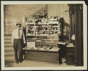 Vak hírkereskedő, John Martie a New York-i Municipal Building déli végében lévő standján alkotó: Company Byron