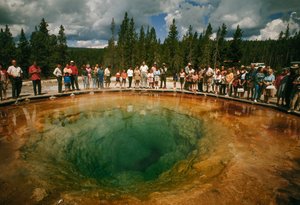 A park látogatói a kékeszöld, virág alakú termálmedence körül gyülekeznek. Yellowstone Nati...