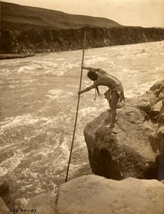 Tlakluit indián, sziklán állva, halászik merítőhálóval, 1910 körül (fekete-fehér fotó) alkotó: Edward Sheriff Curtis