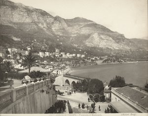 Panorámás kilátás Montecarlóra Monacóban. A jelenet különféle járókelőket mutat be; bal oldalon egy márványkorlát közeli képét látjuk