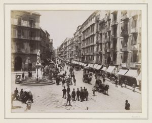 Kilátás a Via Roma utcára Nápolyban, szoborral, üzletekkel, lovaskocsikkal és járókelőkkel