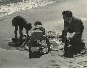 Három gyerek játszik a homokkal a strandon.