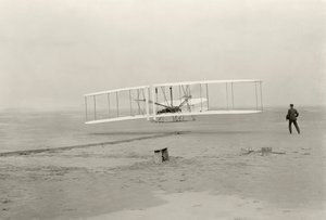 A Wright Flyer I első 120 láb magas repülését 12 másodperc alatt teszi meg az észak-karolinai Kitty Hawkban alkotó: John T. Daniels