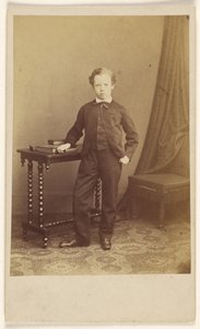 [Azonosítatlan öltönyös kisfiú áll egy asztalnál, rajta könyvekkel] alkotó: Joseph Brown