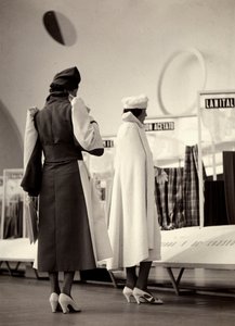 A hátulról látható két modell a "Lamma" couture ház alkotásait viseli. Az egyik modell két tónusú felöltőt visel, derékban öblítéssel. A másik modell teljes köpenyt visel. Az azonos színű kalapok minden együttest kiegészítenek. (f/w fotó) alkotó: Luis Bogino