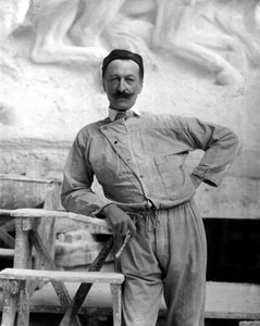 A híres szobrász, Pietro Canonica portréja munkaruhában. A művész műtermében pózol, jobb kezében egy mesterségbeli szerszámot tartva