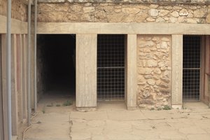 Minoen Knósszosz régészeti lelőhelye. Nyugati szárny a „” háromoldalú szentély” mellett”. Szoba két nagy téglalap alakú, padlóba süllyesztett tárolóval. Tele voltak agyagvázákkal és értékes tárgyakkal, köztük a híres „Kígyót” ábrázoló szobrocskákkal. alkotó: Minoan