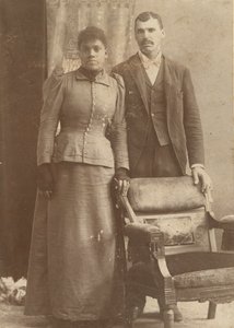 Fénykép egy afro-amerikai házaspárról, amint egy szék mögött áll, kb. 1890. alkotó: Schmitz Studio