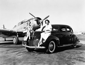 Kalifornia: 1939 Két nő ül egy 1939-es Lincoln Zephyr szedán sárvédőin egy repülőtéren, mögöttük egy hajtóműves gép parkol (f/w fotó) alkotó: Unbekannt