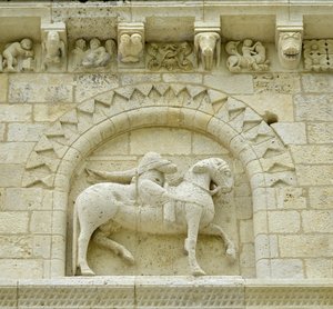 Román művészet: a homlokzat részlete, amely Hugues de Surgeres-t és Geoffroy de Vendome-ot vagy I. Nagy Konstantin császárt ábrázolja, akinek a ló lába Eretnekséget és a gonosz és a halál diadalmaskodó Krisztusát tapossa, Notre Dame (Notre-Dame) de Surgere alkotó: Unbekannt
