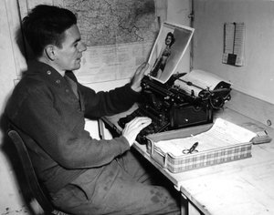 Második világháború (1939-1945) – II. világháború (II. vagy 2. világháború): Mutzig (Elzász) Franciaország 1944. december 1.: Flanerty tizedes, a Beachead News (a GI hírlapja) krónikása ránéz egy fényképre, amelyet itt tesz közzé. az újság következő száma. alkotó: Unbekannt