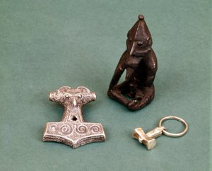 Viking istenségek amulettek: az előtérben két kis ezüst kalapács, amely Thor istent jelképezi. A szobor Freyrt, a termékenység istenét ábrázolja. Stockholmi Történelmi Múzeum, Svédország.