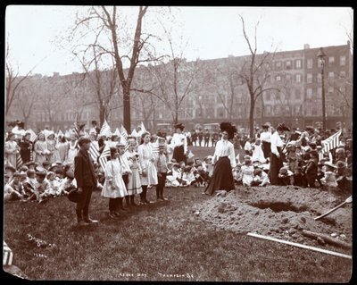 Zászlót tartó felnőttek és gyerekek egy újonnan ásott lyuk körül, ahol egy faültetésre szánták az Arbor Day-t a Tompkins Square Parkban, New York, 1904 (ezüst zselatin nyomat) alkotó: Byron Company