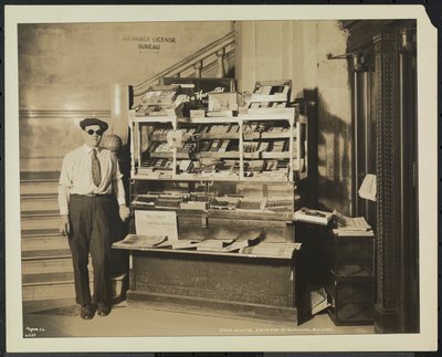 Vak hírkereskedő, John Martie a New York-i Municipal Building déli végében lévő standján alkotó: Company Byron