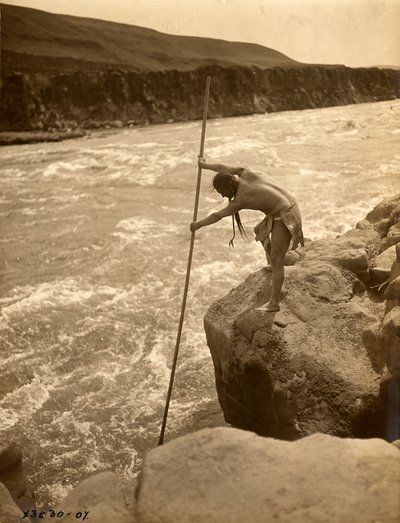 Tlakluit indián, sziklán állva, halászik merítőhálóval, 1910 körül (fekete-fehér fotó) alkotó: Edward Sheriff Curtis