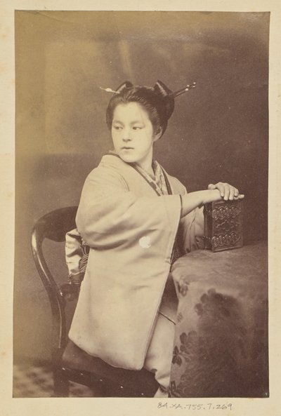 [Ülő japán nő egy cartes-de-visite albumot tart az asztalnál] alkotó: Felice Beato