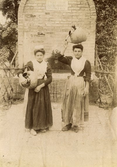 Két fiatal nő hagyományos ruhát visel és terrakotta edényeket cipel kút mellett, Marche, Olaszország, 1910 körül alkotó: Italian Photographer