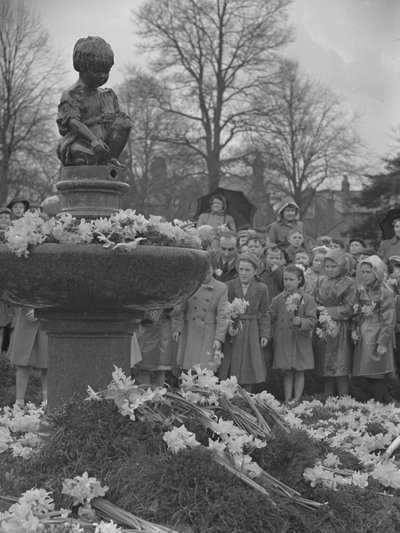 Gyermekek nárciszcsokrokat helyeznek a szökőkútra, amelynek tetején szobor áll alkotó: Joseph Hardman