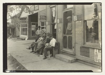 Férfiak kutyával ülnek a padon a General Store előtt alkotó: Lewis Wickes Hine