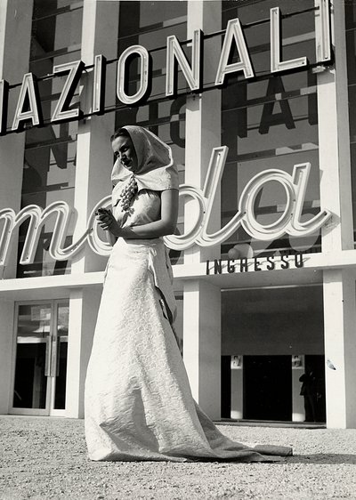 A "Lamma" couture ház által készített esküvői ruha modell. A cikket a szerzetesi stílusú fejdísz jellemzi, amelyet a nyaknál egy mutatós, szőlőfürt formájú tű tartja. (f/w fotó) alkotó: Luis Bogino