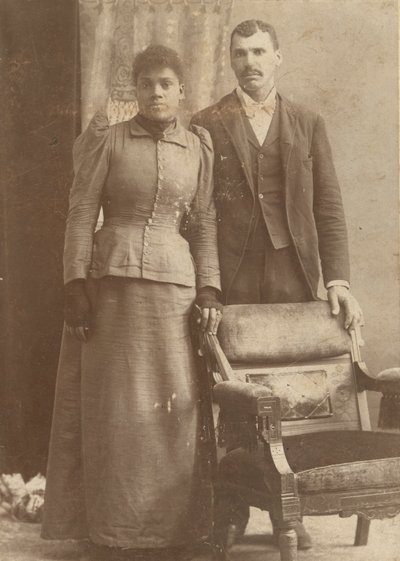 Fénykép egy afro-amerikai házaspárról, amint egy szék mögött áll, kb. 1890. alkotó: Schmitz Studio