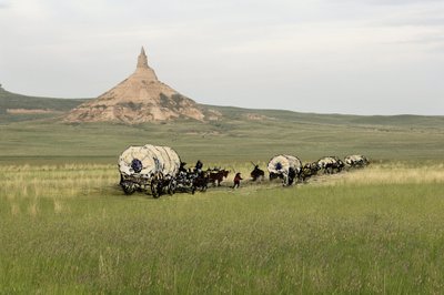 A West Conquete telepesek története: Amerikai úttörők. Több család utazása az Egyesült Államok síkságain szorgalmasan átkelve. Diligenciák átkelése a Chimney Rockon az Oregon Trail-en, Nebraska államban. Színes metszet fotóval kombinálva. alkotó: Unbekannter Künstler