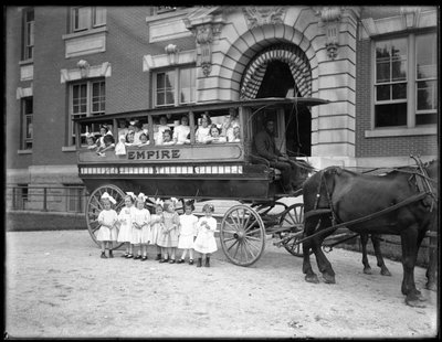 Kislányok pózolnak egy lovas kocsiban és előtte, egy ismeretlen épület előtt, valószínűleg a római katolikus árvamenhely, Kingsbridge, Bronx, 1910 körül alkotó: William Davis Hassler