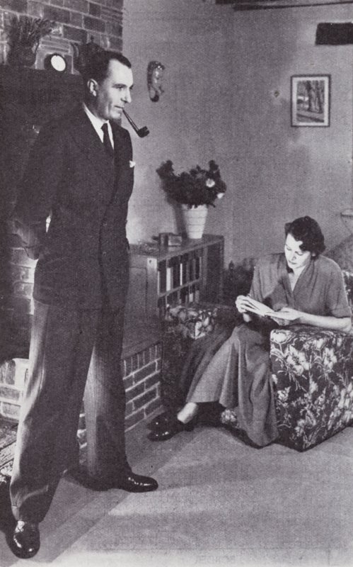 A feleség olvas, míg a férj a tűznek melegíti a hátát, 1950 körül alkotó: English Photographer