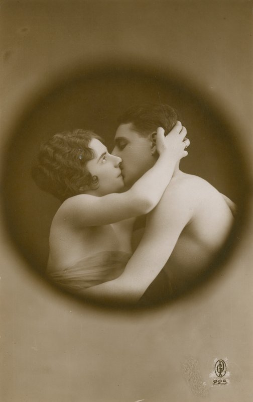 Fiatal férfi és nő csókolóznak egy kukucskálón keresztül nézve. 1913-ban feladott képeslap. alkotó: French Photographer