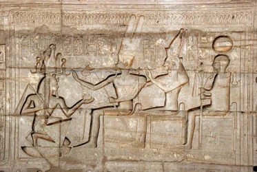 Egyiptomi ókor: II. Ramszesz fáraót ábrázoló dombormű a thébai triász istenségei, Amon, Mut és Khonsu előtt; II. Ramszesz fáraónak (Kr. e. 1279-1213) szentelt temetési templom, a Ramasseum (Ramesseum) helye Luxorban, Egyiptomban.