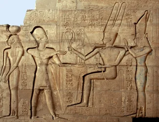 Egyiptomi ókor: II. Ramszesz fáraót a thébai triász két istensége, Ámon és Mut előtt ábrázoló dombormű; II. Ramszesz fáraónak (Kr. e. 1279-1213) szentelt halotti templom, a luxori Ramesseum helyszíne, Egyiptom.