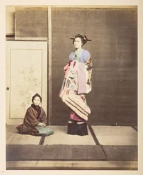 [?Geisha, ] Egész alakos műteremportré egy fiatal nőről, magasított cipőben, fiatal kísérője mellette térdelve a földön,   Fotós: Ismeretlen  Lucas Collection: Charles James és Morton P, Luc világkörüli turnéjának fényképfelvétele