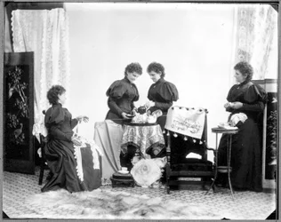 Hannah Maynard többszörös expozíciója - ketten teáznak, egyikük pamutfonalgombolyagot tart, egyikük gombolyaggá tekeri, kb. 1895