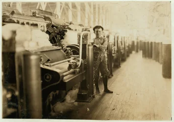Söprögető fiú a kártológépek mellett a Lincoln Cotton Millsben, Evansville, Indiana, harisnyás lábakkal a csúszós padlón, 1908