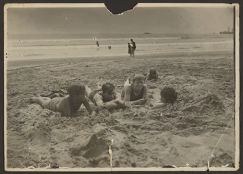[Gyerekek fekszenek a homokban a strandon]