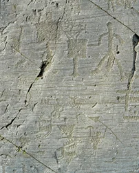 Őskor, camunni civilizáció, sziklaművészet: sírszikla szarvasvadászatot és egy falu mindennapi életét ábrázoló jelenetekkel. Az újkőkor és a bronzkor közötti időszak. Capo di Ponte, Parco nazionale delle incisioni rupestri di Naquane, Valcamonica, Val
