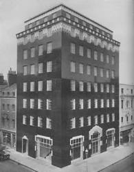 Egy teljesen fekete épület Londonban, csipkeszerű fehér gallérral kiemelve, kb. 1935