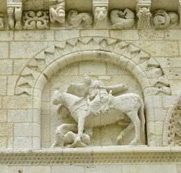 Román művészet: a homlokzat részlete, amely Hugues de Surgeres-t és Geoffroy de Vendome-ot vagy I. Nagy Konstantin császárt ábrázolja, akinek a ló lába Eretnekséget és a gonosz és a halál diadalmaskodó Krisztusát tapossa, Notre Dame (Notre-Dame) de Surgere