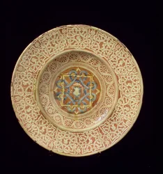 Maiolica tányér, kidolgozott, ismétlődő csomómintával díszített profilfejeket keretező szegélyen és pajzs a központi táblában, olasz, Toszkánában
