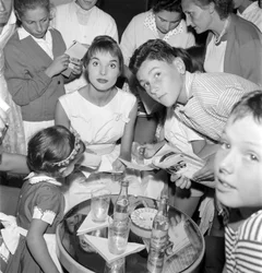 ELSA MARTINELLI SZÍNÉSZNŐ ÉS DIVATMODELL A XVIII. NEMZETKÖZI FILMFESZTIVÁLON, A VELENCEI LIDÓN (fiatal rajongóknak ad autogramot. Az asztalon egy üveg Schweppes áll) - 1957