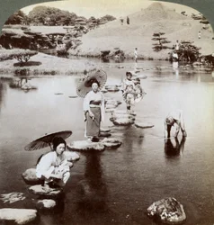 Nők átkelnek a tavon lépcsőkövön, Suizen-ji kert, Kumamoto, Japán, 1904.