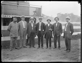 Hét azonosítatlan férfi pózol egy folyó vagy tó közelében, 1910 körül