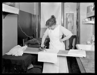 Azonosítatlan nő, aki egy elektromos vasaló használatát demonstrálja 1913-14 körül
