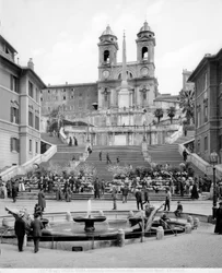 Kilátás a Piazza di Spagna-ra: az előtérben a Fontana della Barcaccia, a lépcsőn túl egy obeliszk és a Trinità dei Monti templom.